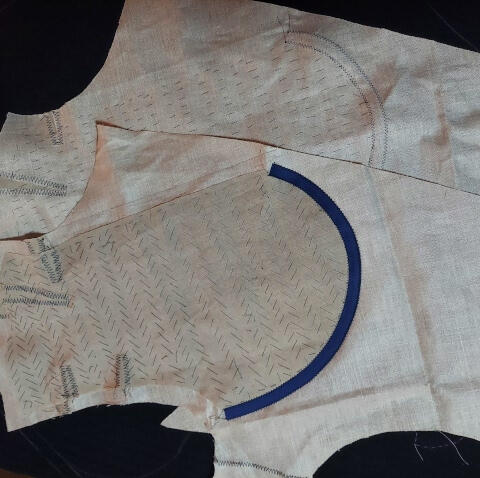 Muslin, canvas, and stitching form some of the inner structure of custom suit jacket on top of black suiting fabric